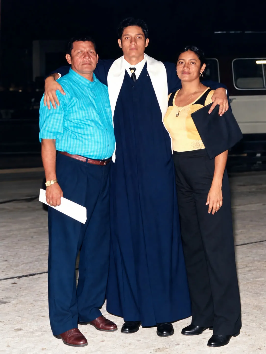 Tres personas de una familia posando juntas de noche